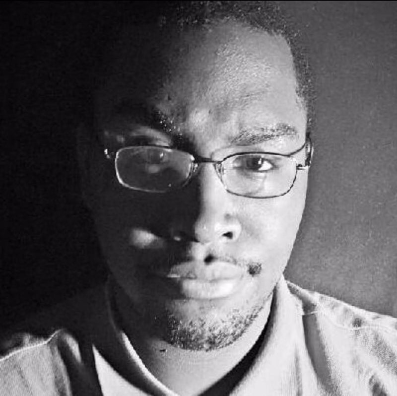 Black and white portrait of a person wearing glasses with a dark background