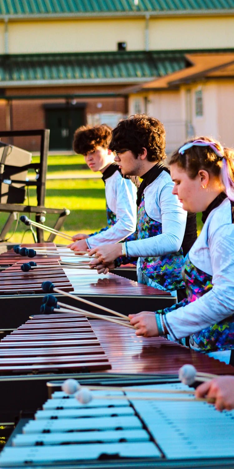 People playing marimbas with a building in the background